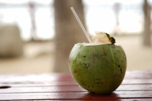 a picture of a green coconut with the top taken off and a straw sticking out so you can drink the juice