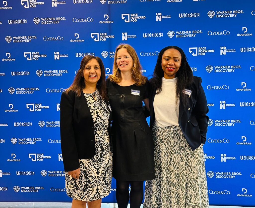 Three women stood in front of the UnderOne festival banner. Bep Dhaliwal, Toni Kent and Aduke Onafowokan